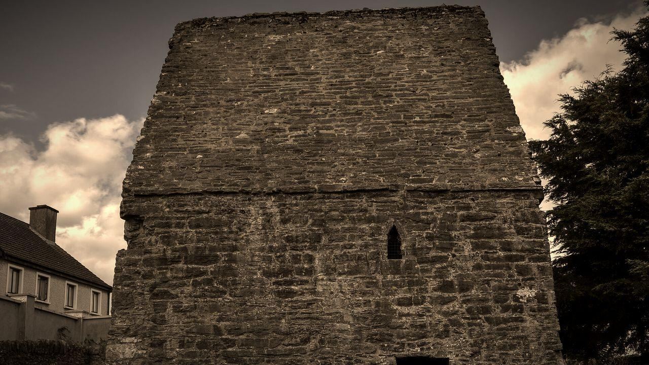 St Colmcille’s House in Kells, a 9th-century stone oratory with a steep stone roof, under a cloudy sky